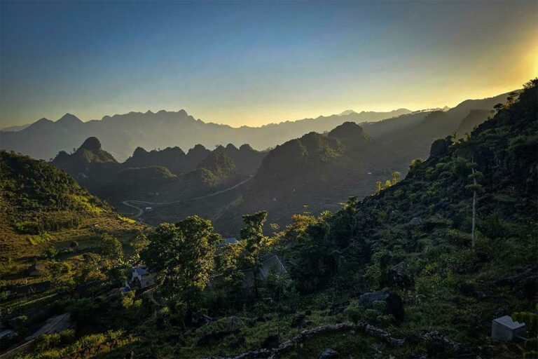 Uitzicht vanaf Ha Giang Aya Lodge over bergpieken in avondlicht tijdens zonsondergang.