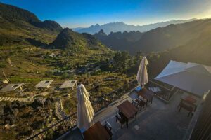 Terras van Ha Giang Aya Lodge bij zonsondergang met uitzicht over groene valleien en karstbergen.