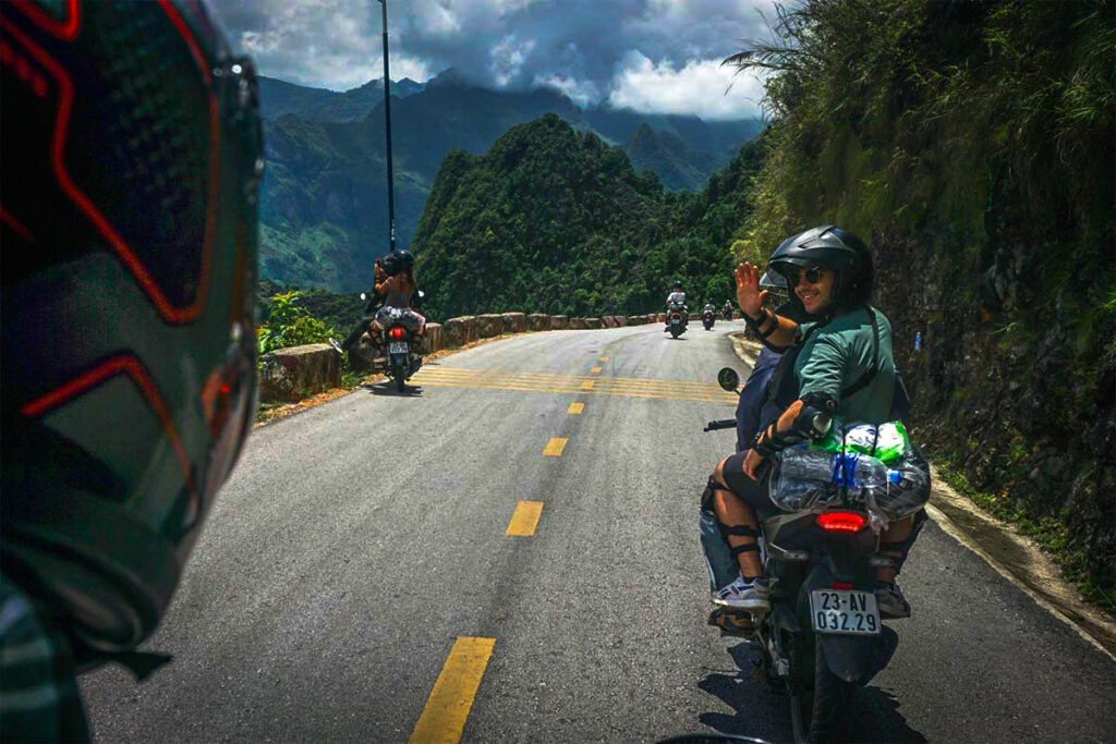Reizigers op een Easy Rider motorbiketocht langs de Ha Giang Loop, rijdend door hoge bergpassen met panoramisch uitzicht.
