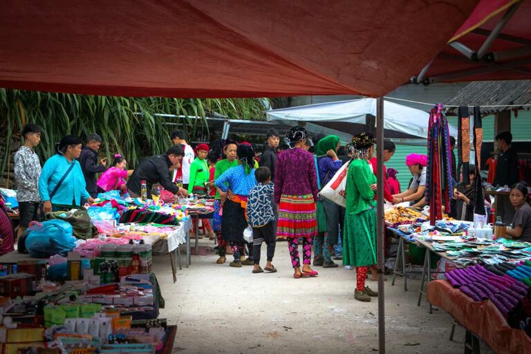 Kraampjes en kleurrijk geklede etnische minderheden op de Sung Trai-markt in Ha Giang.