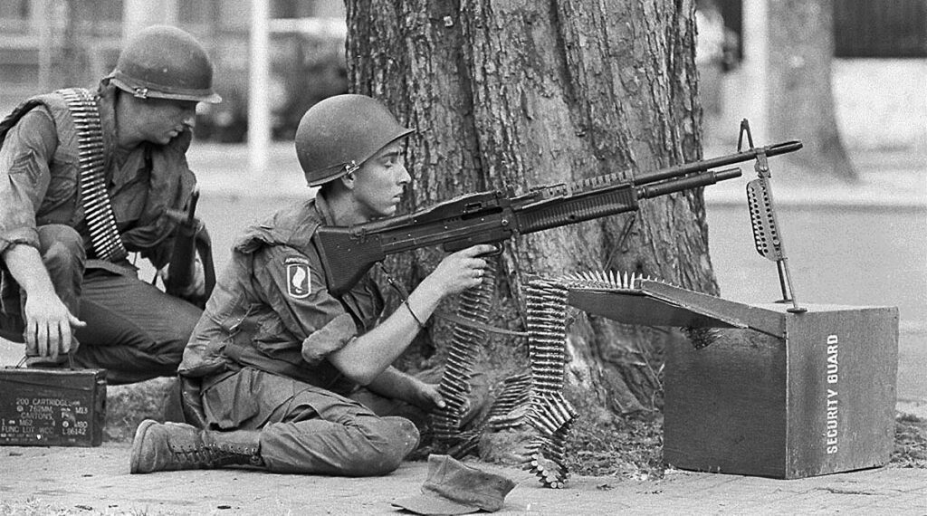 Amerikaanse troepen schuilen achter een boom tijdens de Vietnamoorlog