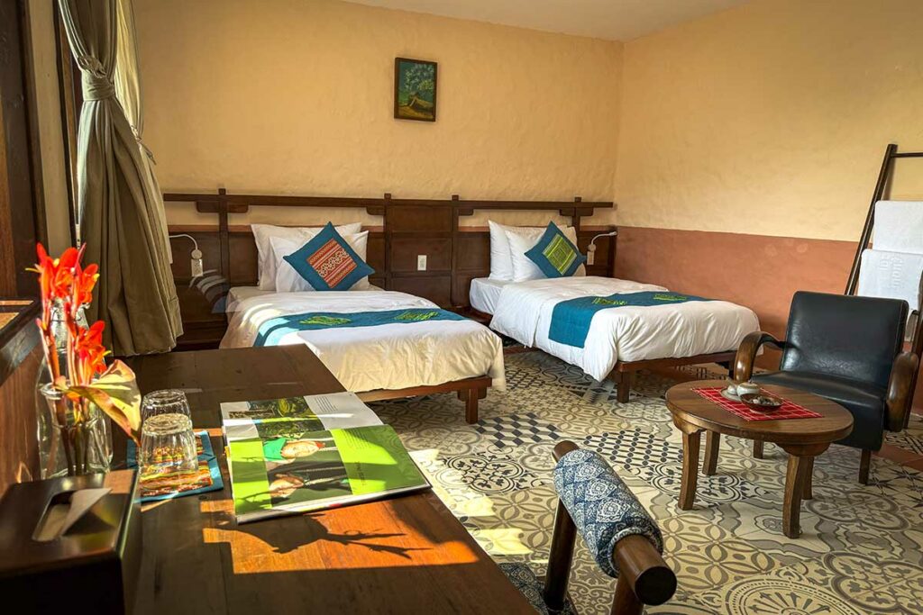 Familiekamer van Ha Giang Aya Lodge met twee bedden, zithoek en natuurlijk licht.