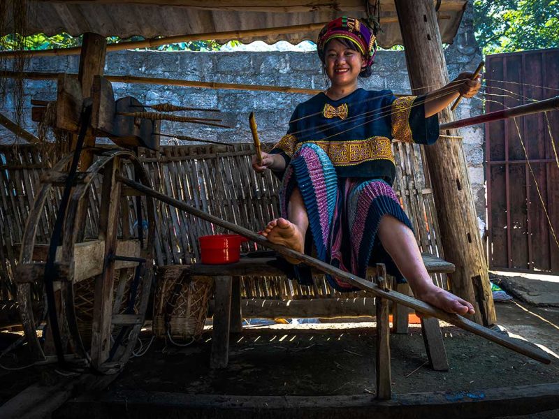 Hmong-vrouw in Lung Tam die handgesponnen draden maakt bij traditioneel weefgetouw