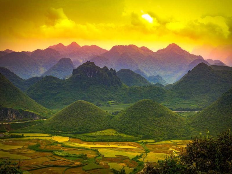 Quan Ba Twin Mountains in het zachte ochtendlicht met groene valleien en rijstvelden eromheen.